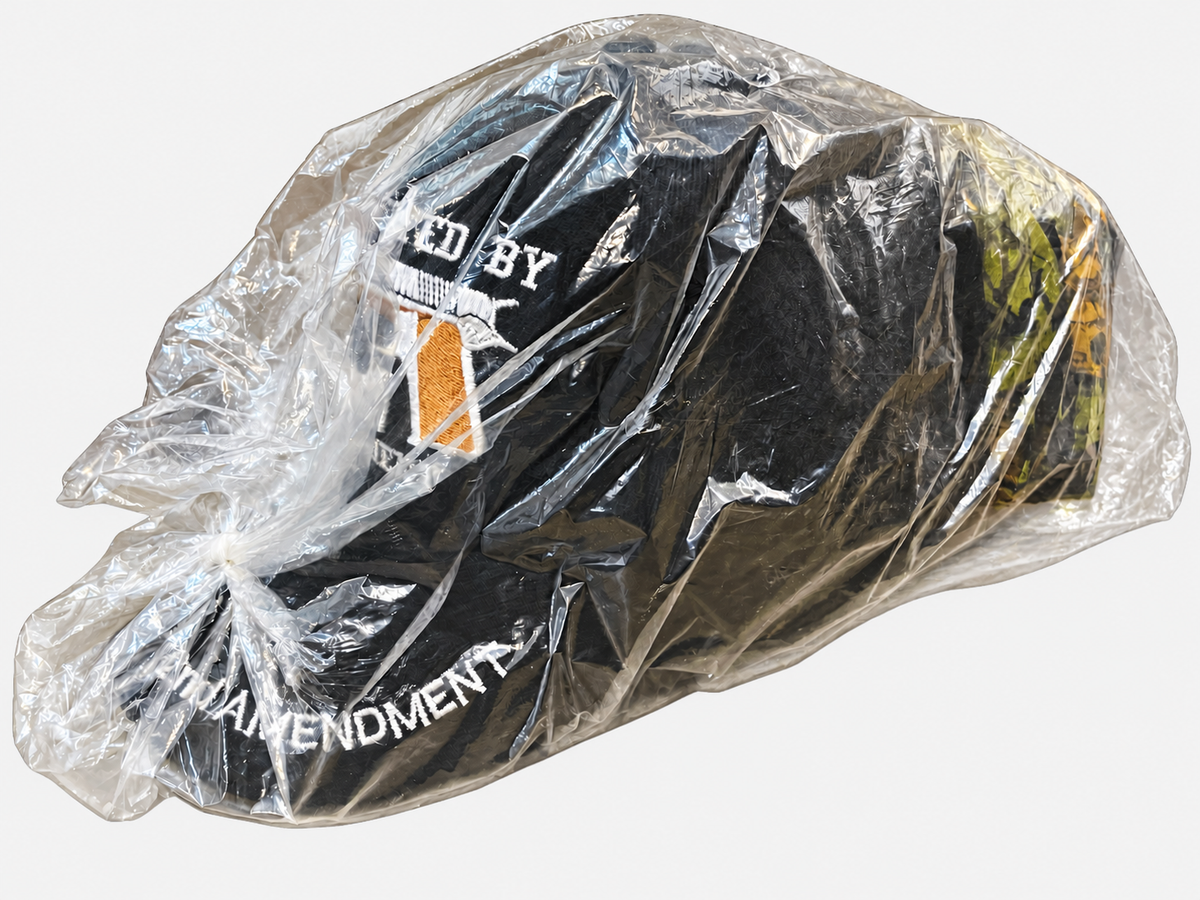 Side view of bagged 2nd Amendment caps on a light gray background
