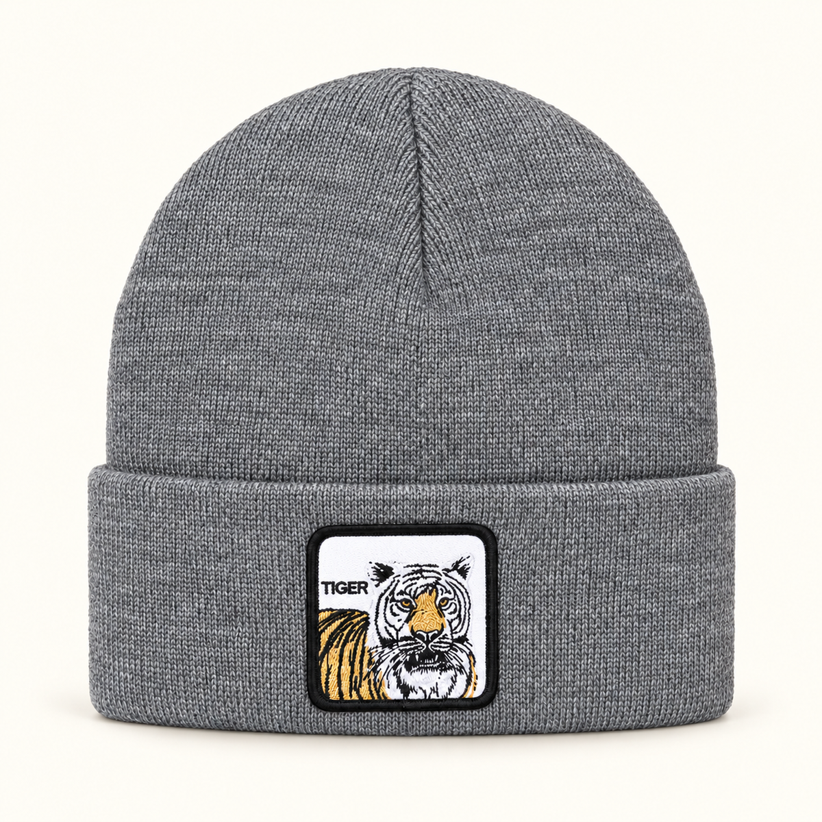 Gray tiger-patch knit beanie, single hat on a clean off-white background.
