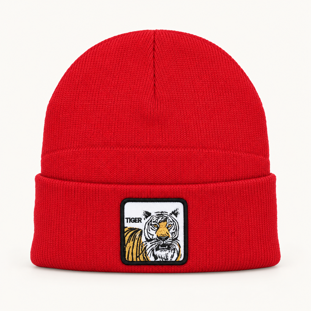 Red tiger-patch knit beanie, single hat on a clean off-white background.