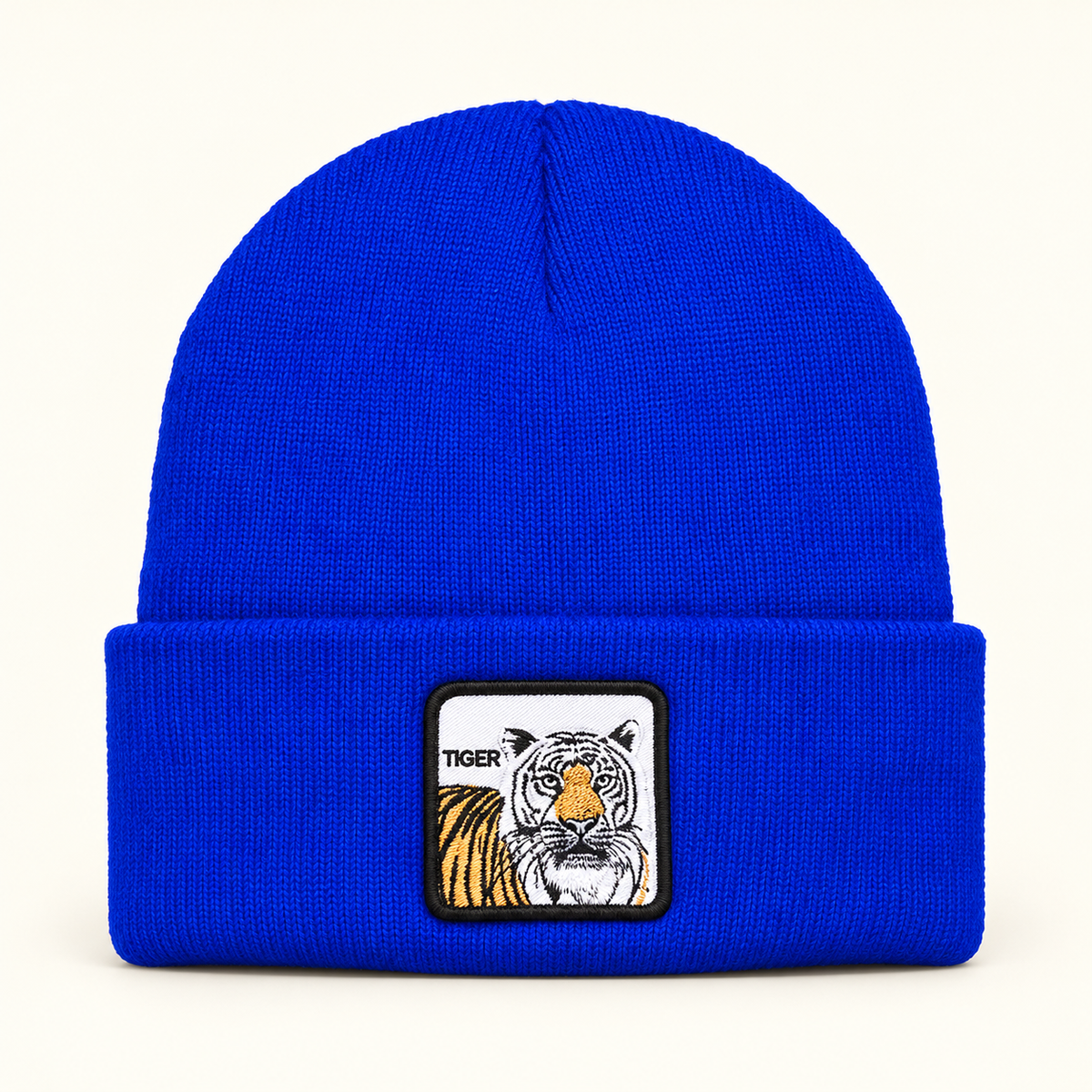 Royal Blue tiger-patch knit beanie, single hat on a clean off-white background.
