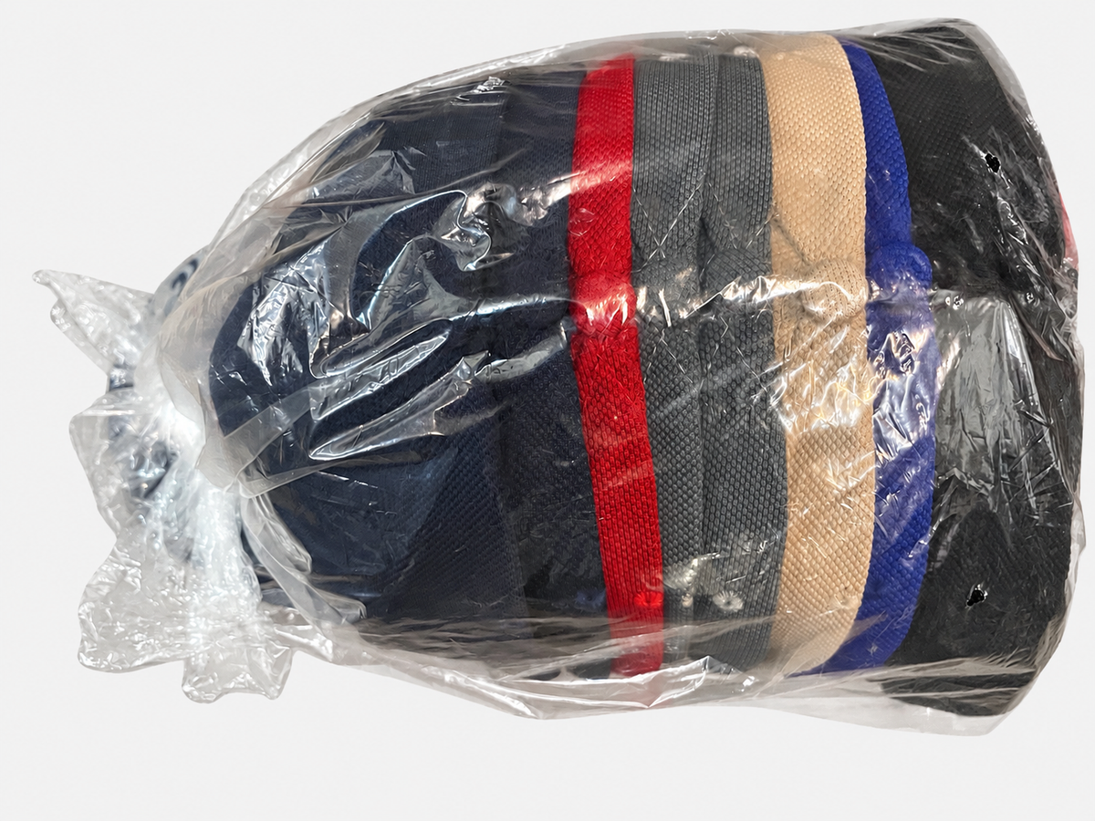 Top view of assorted USA flag eagle-brim caps in clear dozen packaging on a light gray background